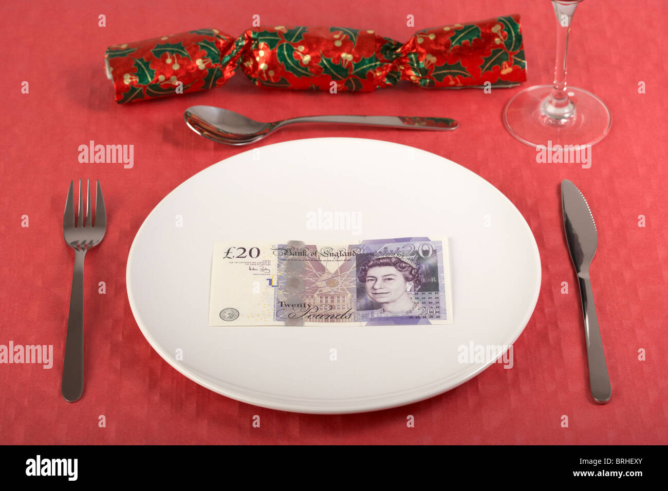 Vingt livres billet sur une assiette blanche nappe rouge sur place et Christmas Cracker Banque D'Images