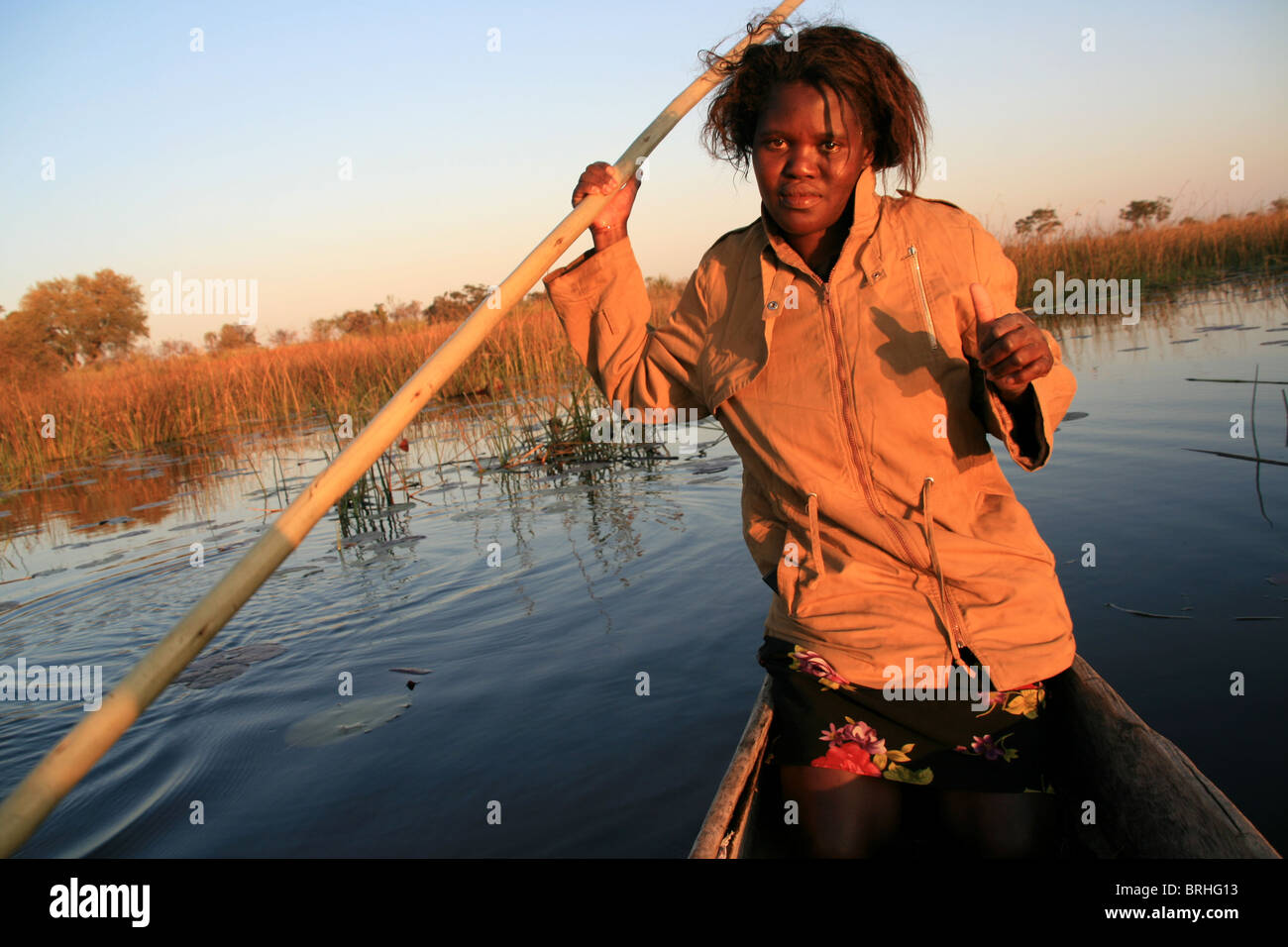 Une femme dirige un bateau dans le Delta de l'Okavango, au Botswana. Banque D'Images