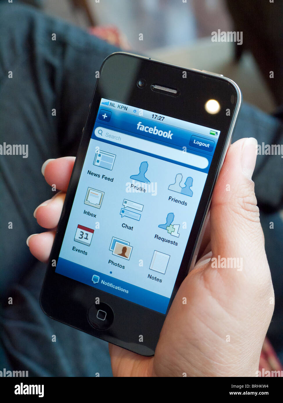 Femme tenant l'iPhone 4G pour contrôler le réseau social Facebook Banque D'Images