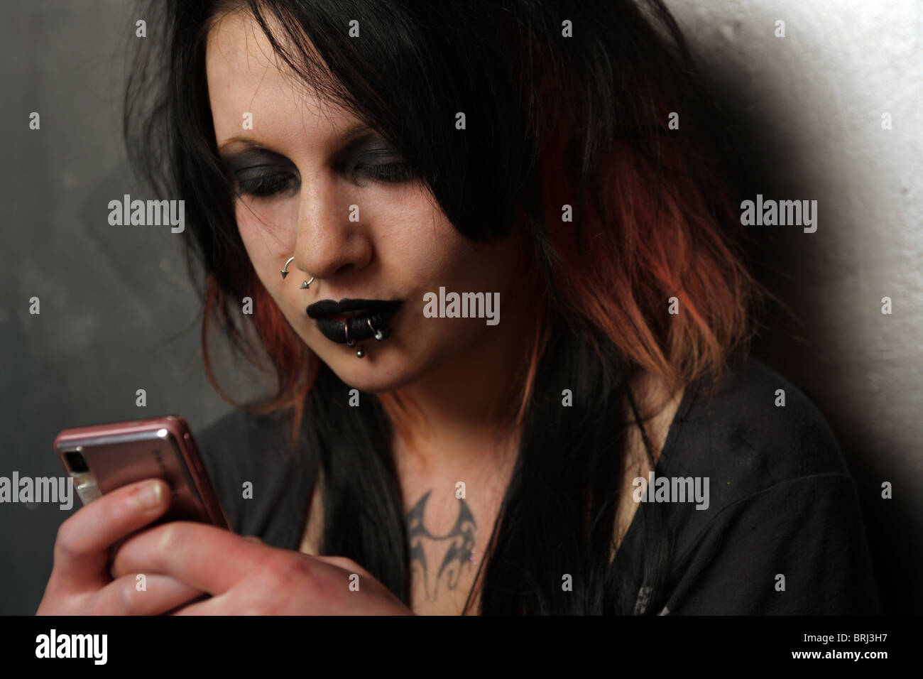 Goth woman holding a mobile phone dans ses mains. Banque D'Images