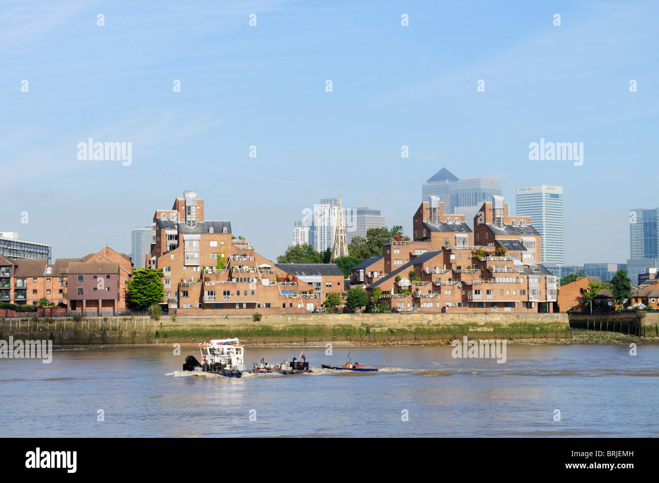Un remorqueur passant sur la Tamise et Canary Wharf Apartments Riverside sur l'Isle of Dogs, Docklands, London, England, UK, Banque D'Images