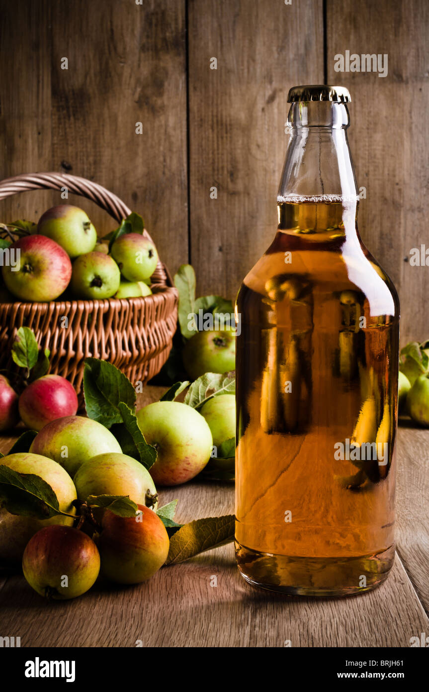 Flacon plein de cidre avec panier de pommes Banque D'Images