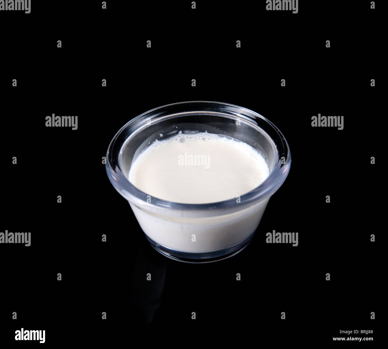 Photo gros plan de crème blanche dans une petite tasse ingrédients claire sur un fond noir Banque D'Images