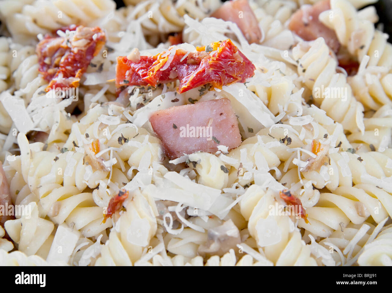 Bacon et pâtes aux tomates séchées aux champignons et parmesan dans un bol noir Banque D'Images