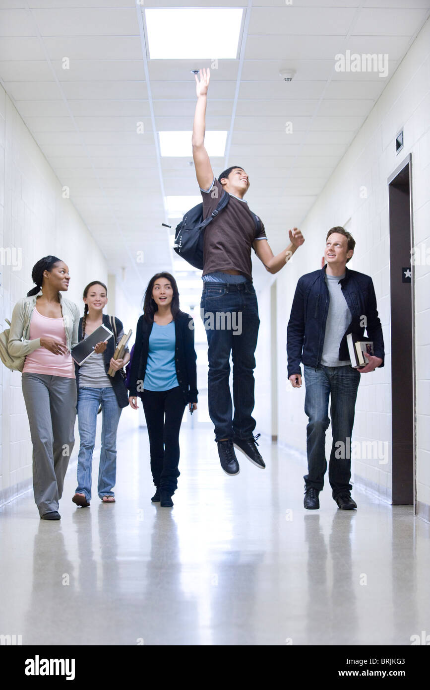 Les élèves du secondaire de couloir d'école regardant ami jumping Banque D'Images