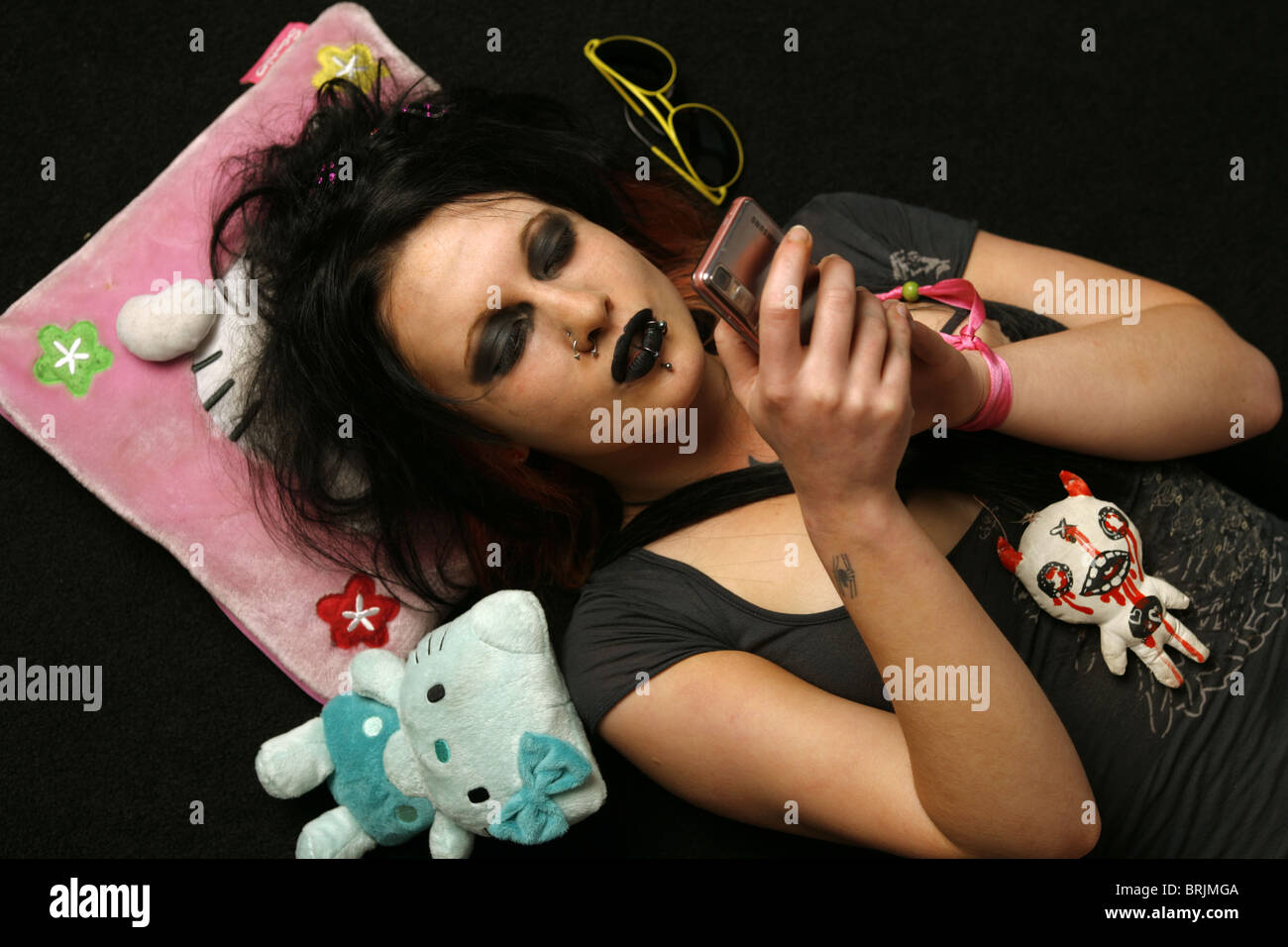 Teenage girl goth couché sur son dos tenant un téléphone mobile. Banque D'Images