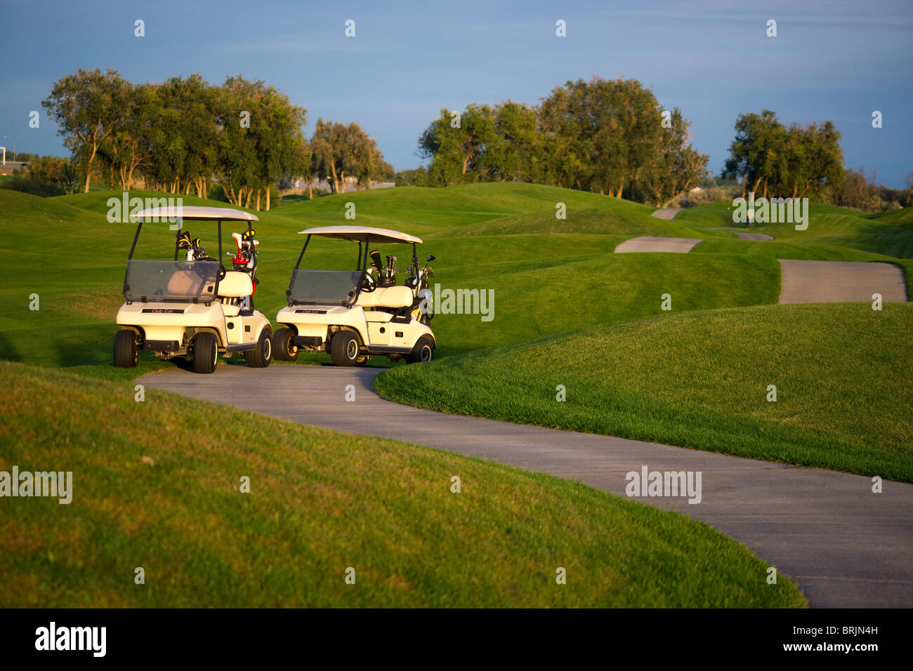 Deux chariots de golf sur un chemin sinueux d'un terrain de golf sur une journée ensoleillée. Banque D'Images