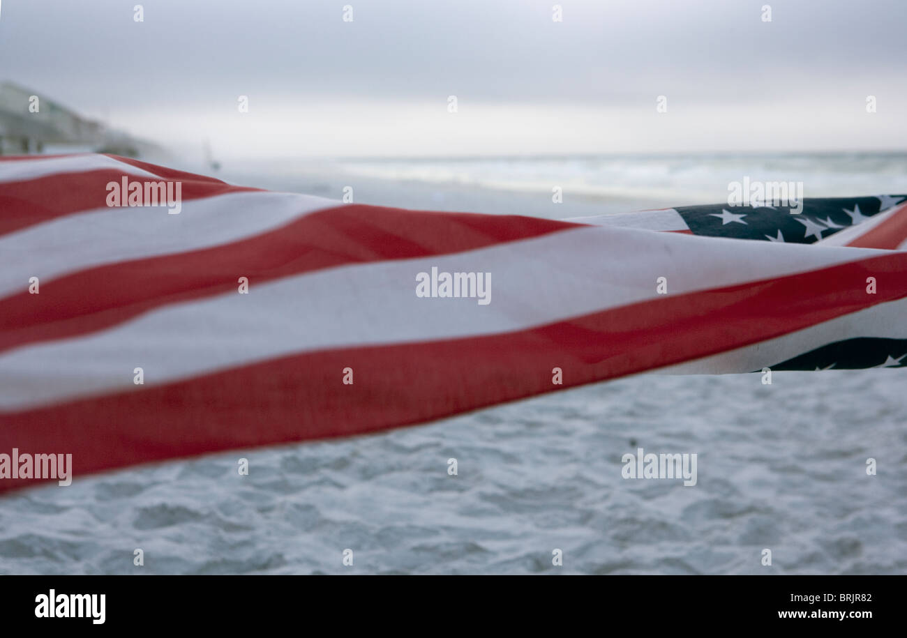 Un drapeau Américain est dans le premier plan avec la plage et l'océan en arrière-plan. Banque D'Images