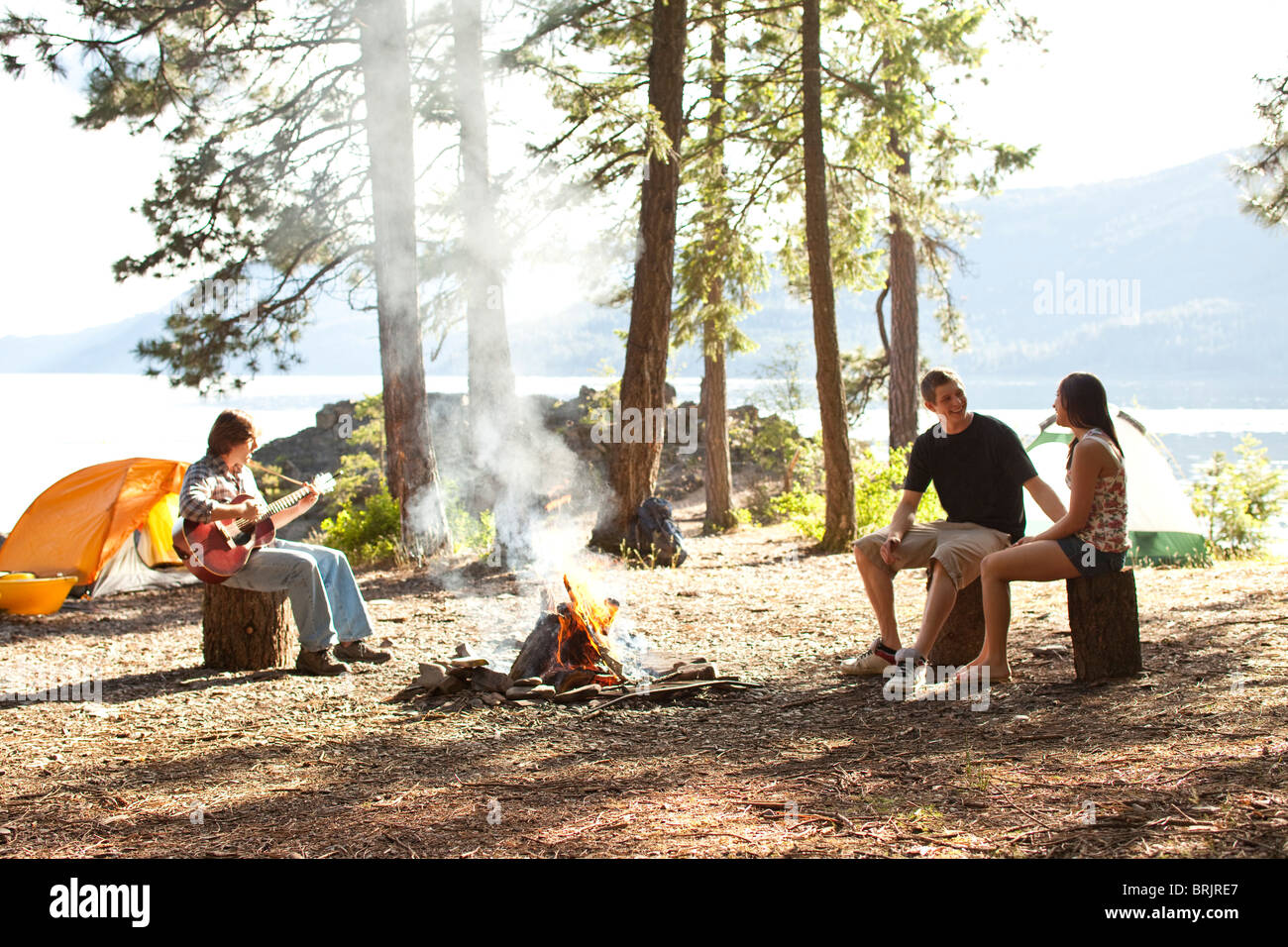 Les jeunes adultes camping s'asseoir autour d'un feu à côté d'un lac dans l'Idaho. Banque D'Images