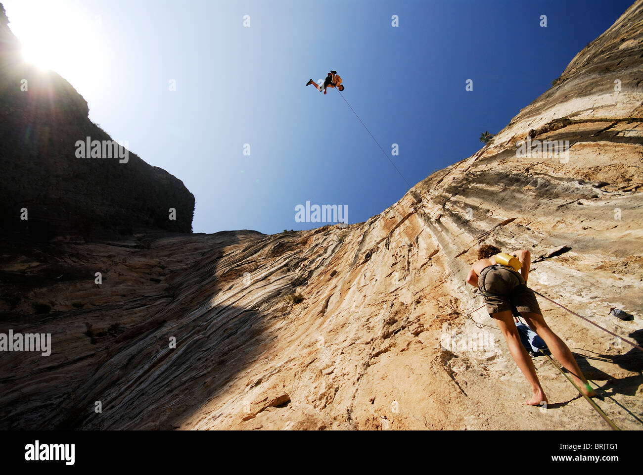 Un grimpeur hors pousse en l'air tandis que la descente en rappel au-dessus d'un autre grimpeur. Banque D'Images