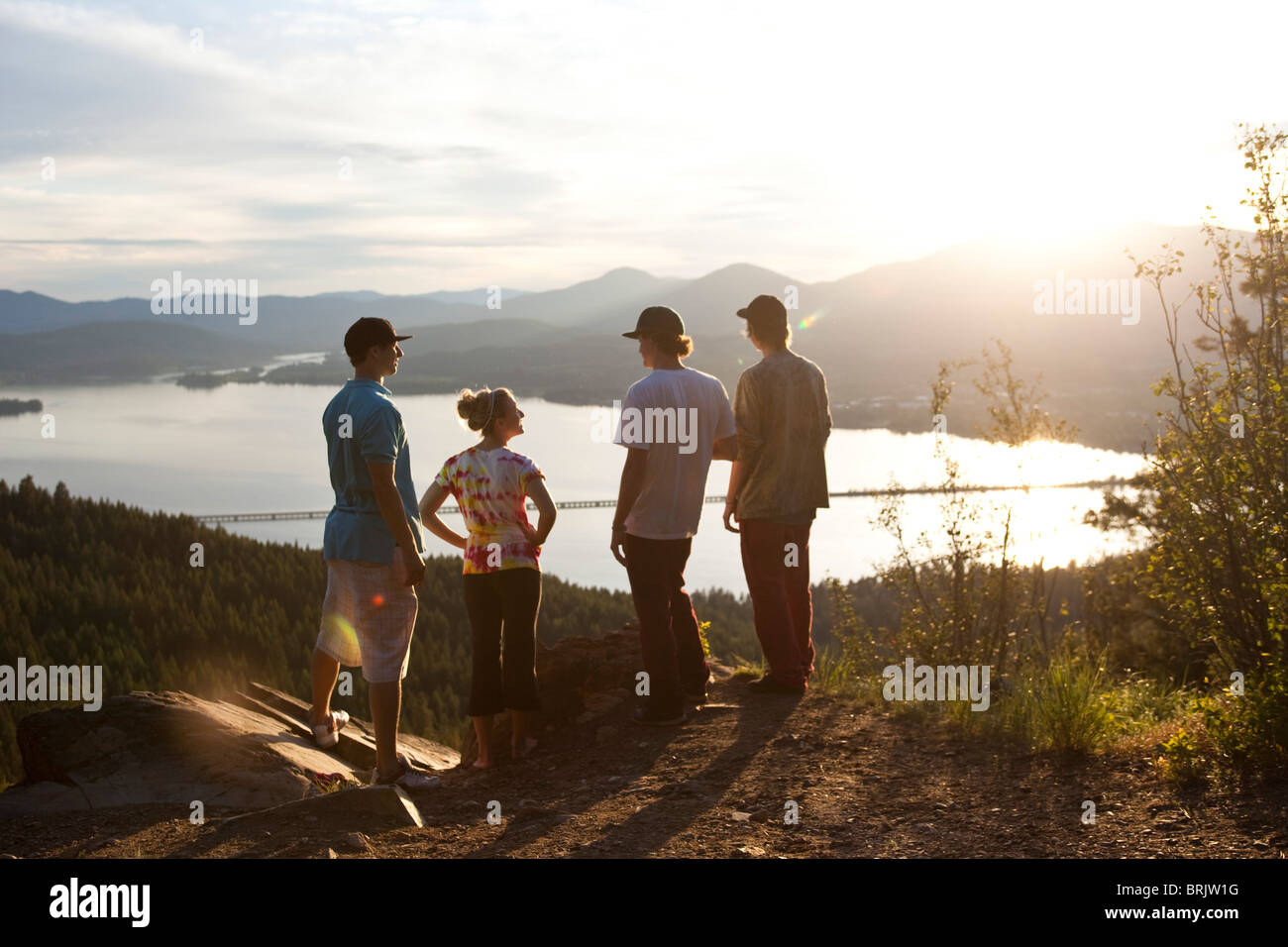 Quatre jeunes amis adultes parler et apprécier la vue après une randonnée au coucher du soleil. Banque D'Images