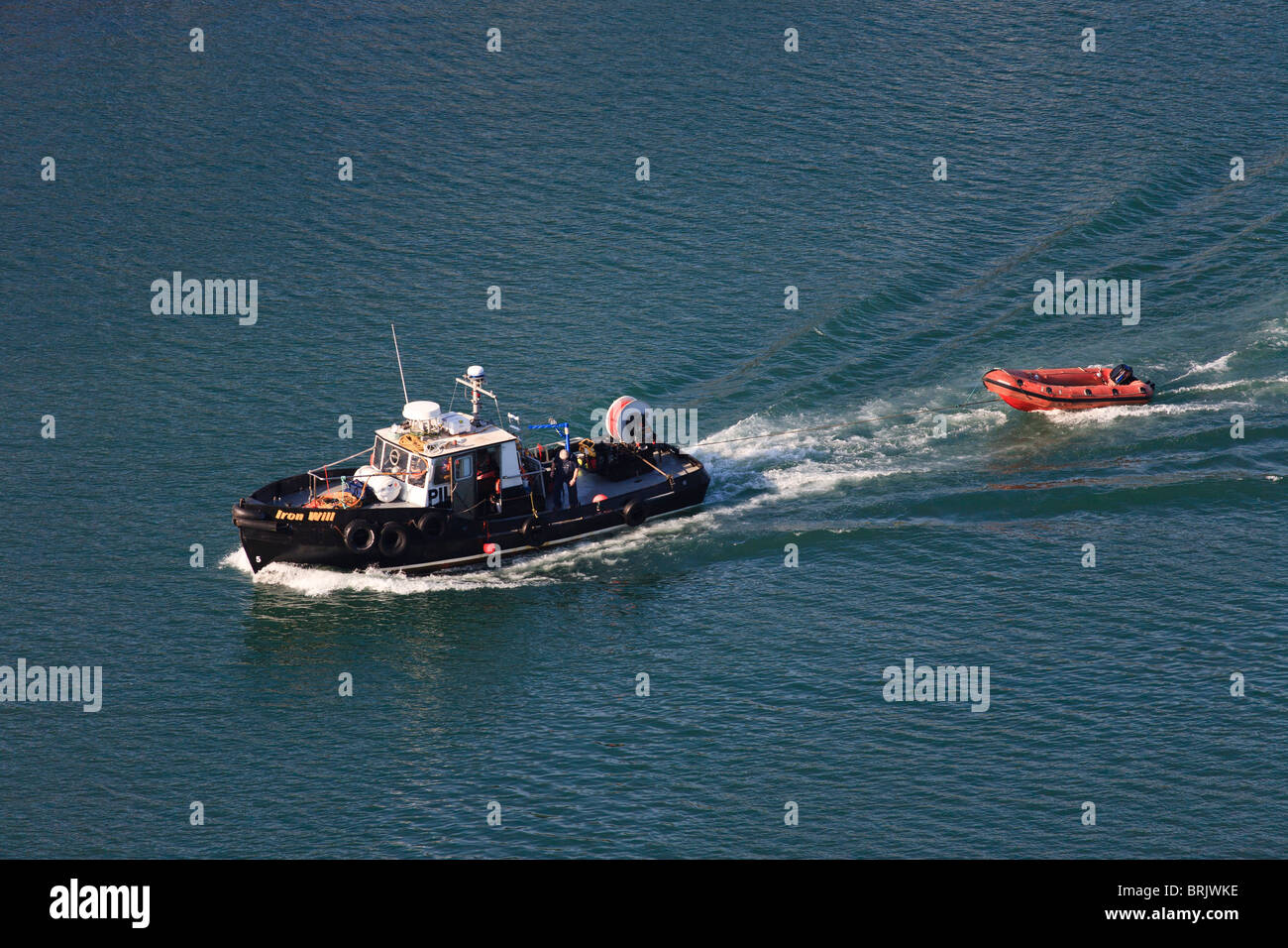 Bateau pilote en vertu du pouvoir du remorquage d'un bateau gonflable orange Banque D'Images