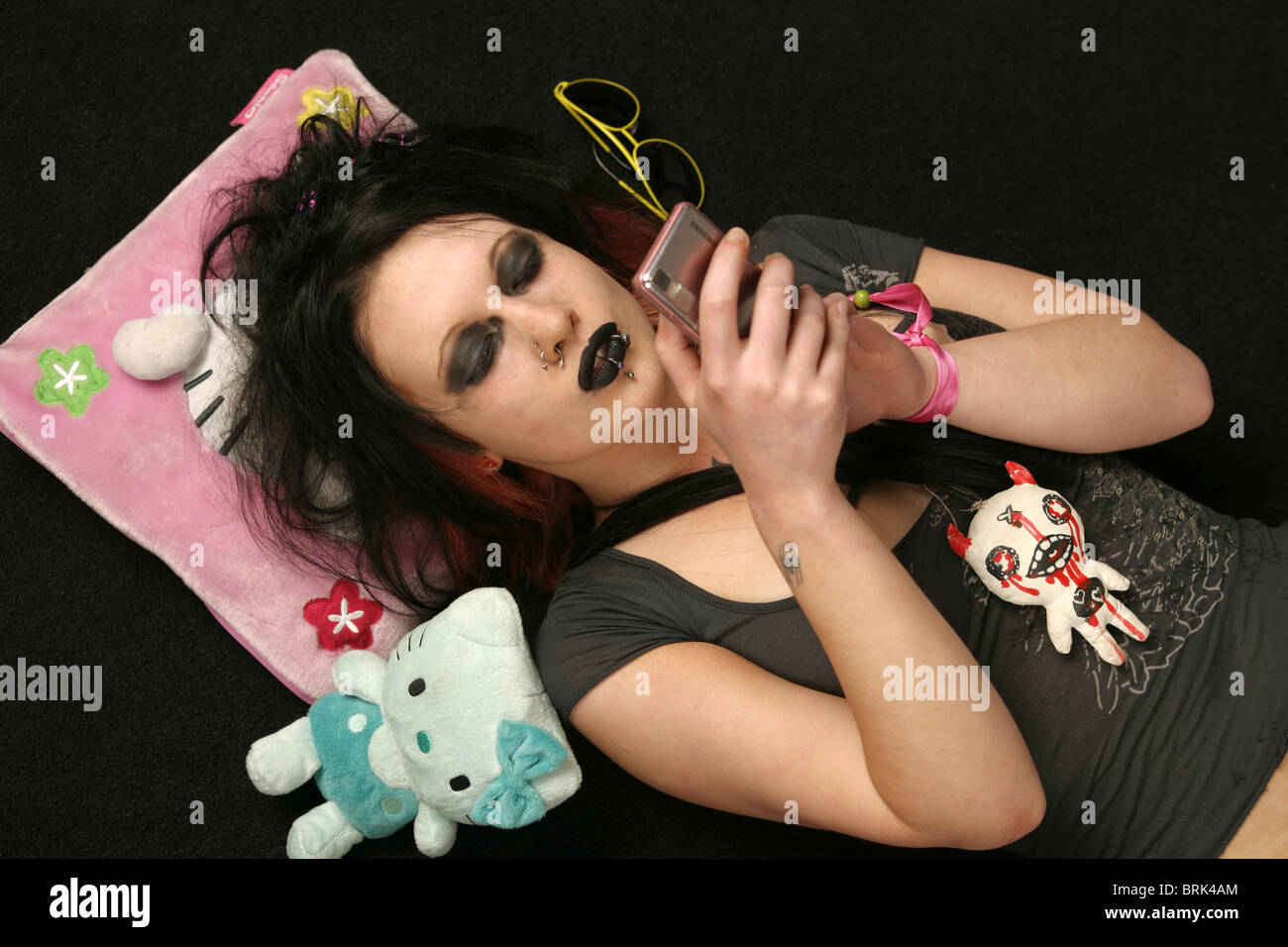Teenage girl goth couché sur son dos tenant un téléphone mobile. Banque D'Images