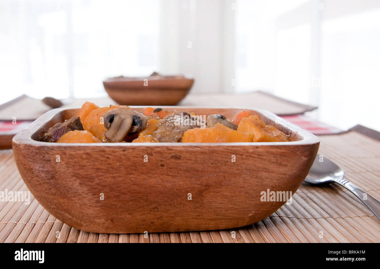 Deux bols de ragoût de boeuf maison avec des carottes et des patates douces dans un bol en bois sur napperon. high key Banque D'Images