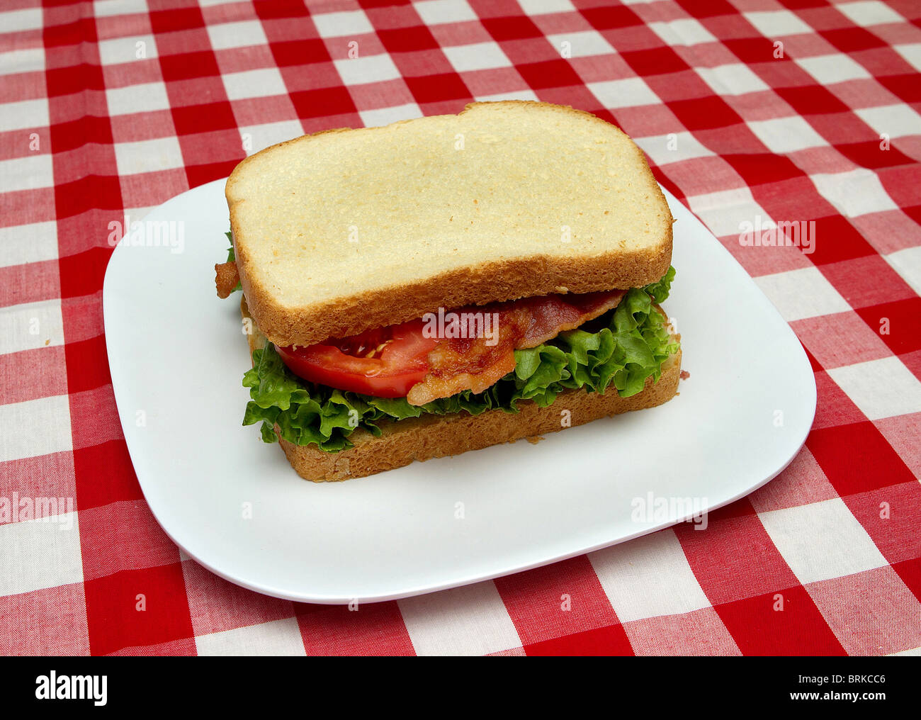Ensemble complet sandwich BLT sur une plaque blanche avec fond rouge vérifié Banque D'Images