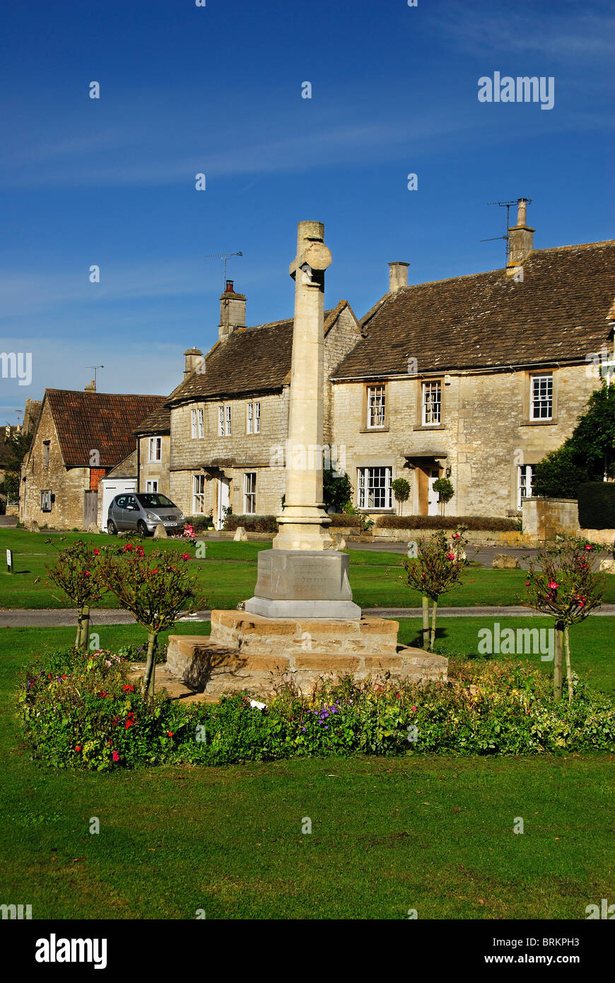 Croix du souvenir sur village green, Biddlestone, Wiltshire, entouré de roses et de maisons en pierre UK Septembre 2010 Banque D'Images