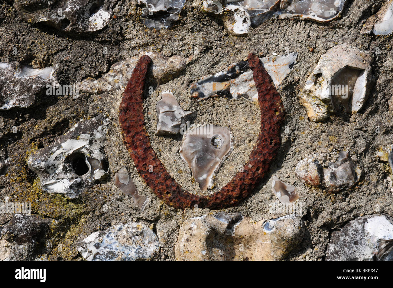 Horsehoe intégré dans l'ancien mur en silex pour la chance. Charlton village, West Sussex. Banque D'Images