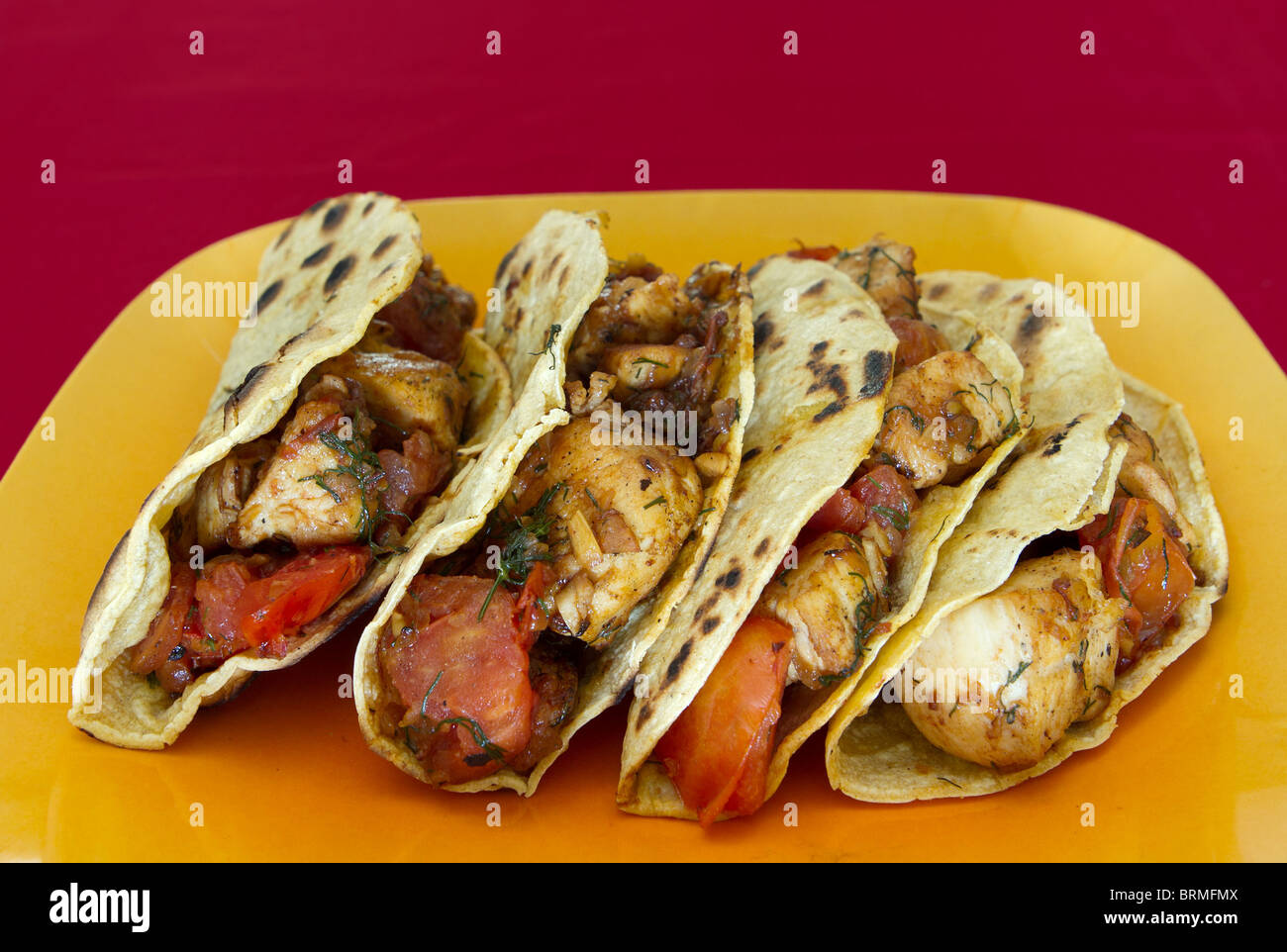 Tacos de poulet à la tomate et herbes complète sur une plaque jaune Banque D'Images