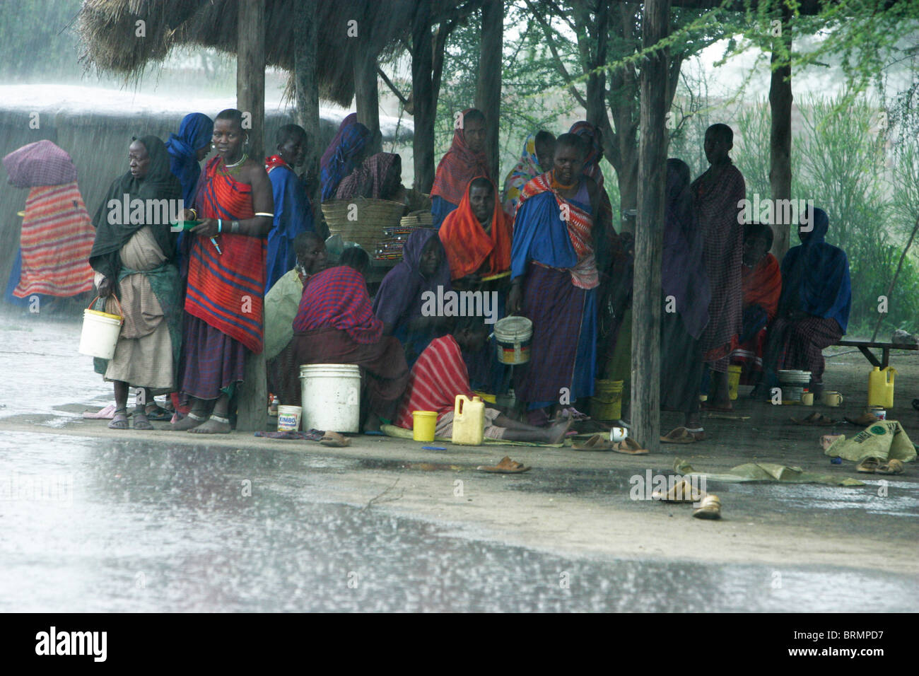Les villageois maasai s'abritant sous une structure de chaume pendant une tempête de pluie Banque D'Images