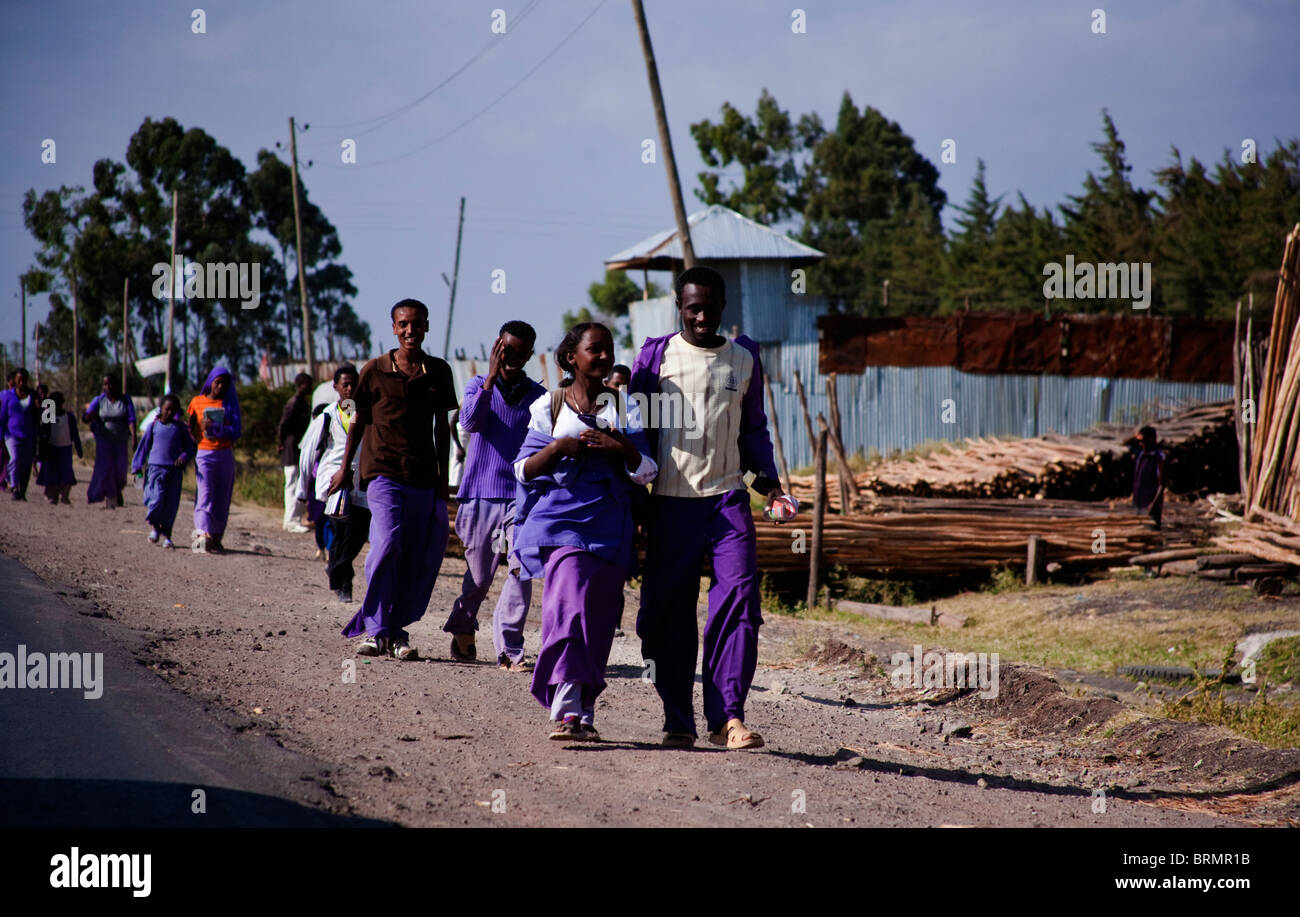 Les spécialistes de l'uniforme mauve marcher sur le bord de la route comme ils marchent à la maison de l'école à la périphérie d'Addis Abeba Banque D'Images