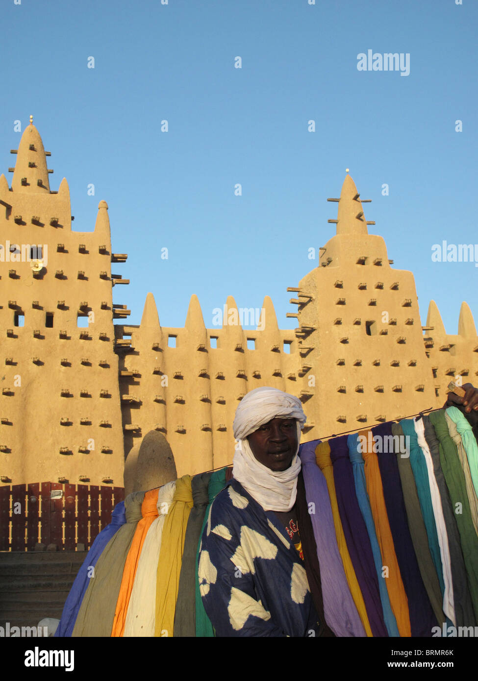 Vente d'un homme en face de turbans colorés Djenné mosquée, la plus grande structure de boue dans le monde, construit en 1907 Banque D'Images