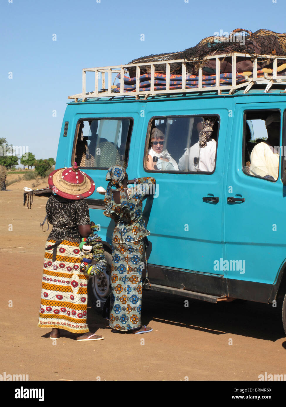 Femme portant des vêtements traditionnels qui vendent leurs produits aux touristes assis dans un autobus bleu Banque D'Images