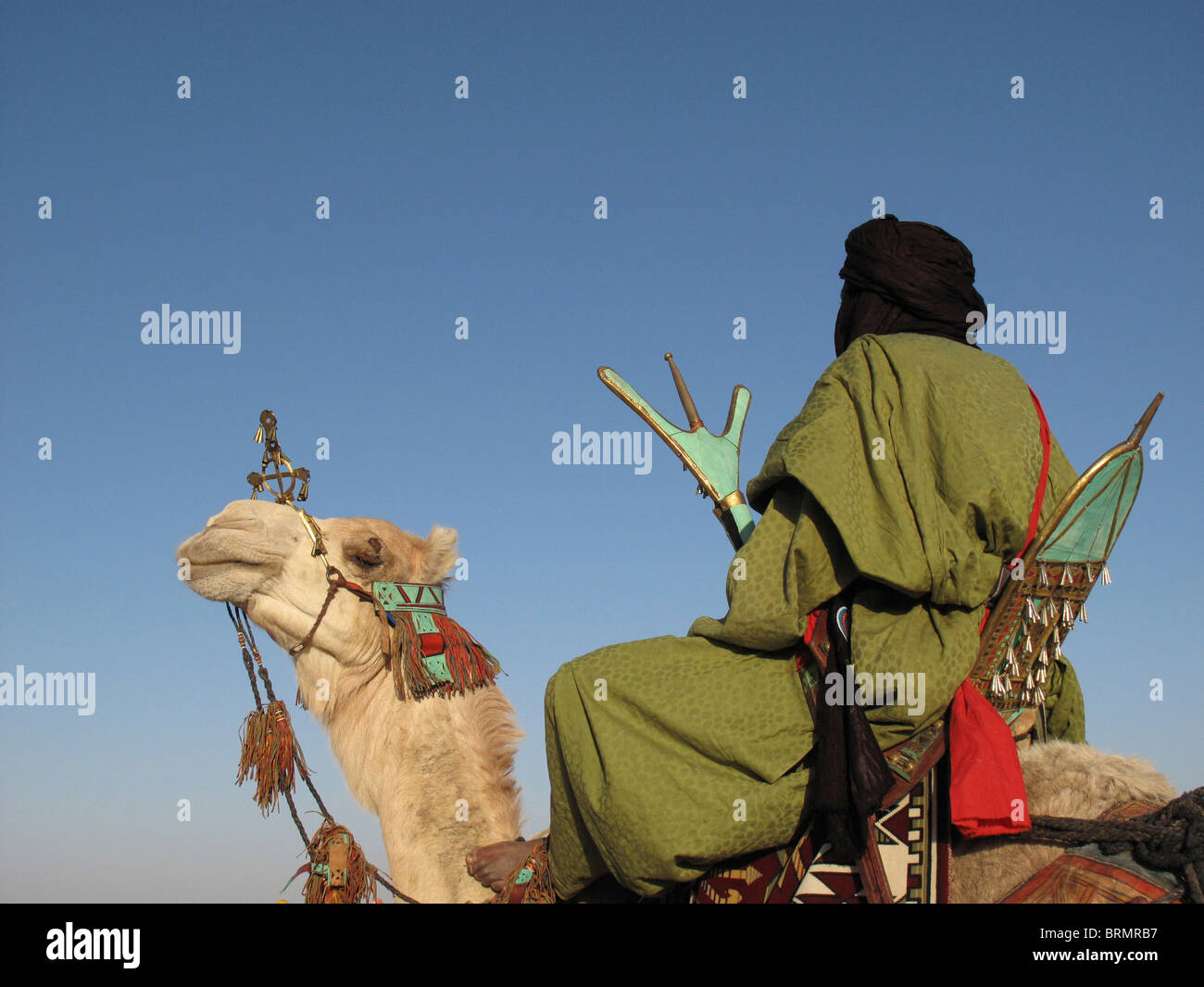 L'homme sur un chameau touareg vêtus de robes traditionnelles en regardant un spectacle au festival annuel dans le désert Banque D'Images