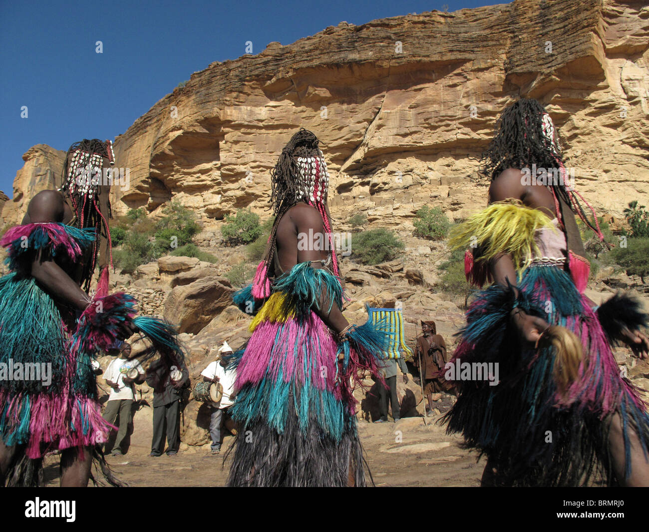 Les danseurs Dogon portant des masques et de longues jupes de paille colorée effectuant une danse de cérémonie Banque D'Images