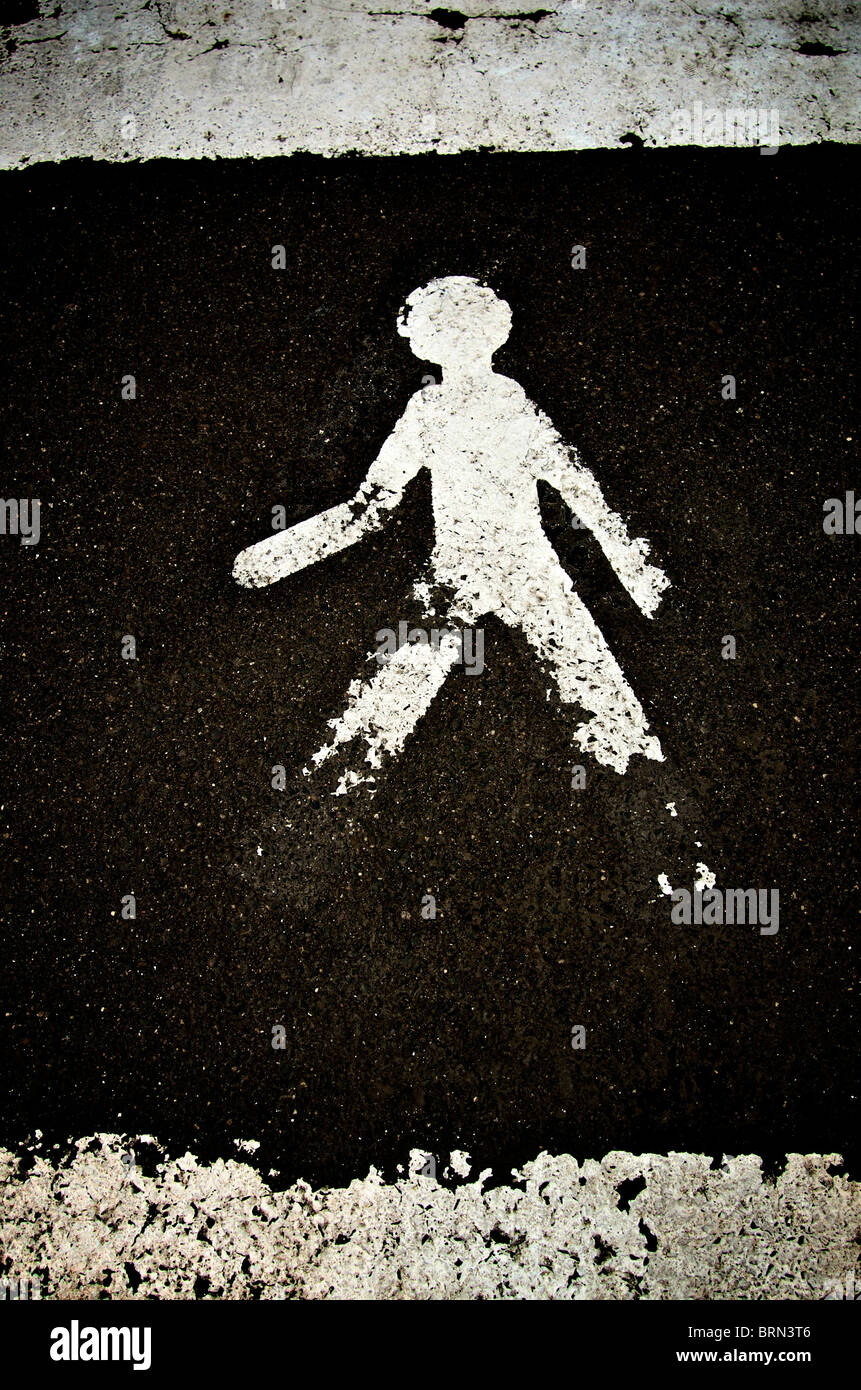 Conception d'un symbole de piéton peint sur une surface de route sombre indiquant une zone de marche pour la sécurité Banque D'Images