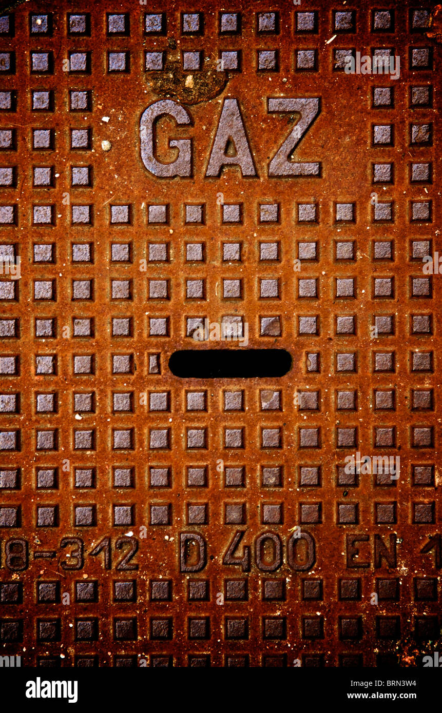 Couvercle de trou d'homme affichant le mot gaz et le motif de grille dans un environnement urbain capturé pendant les heures de lumière du jour Banque D'Images