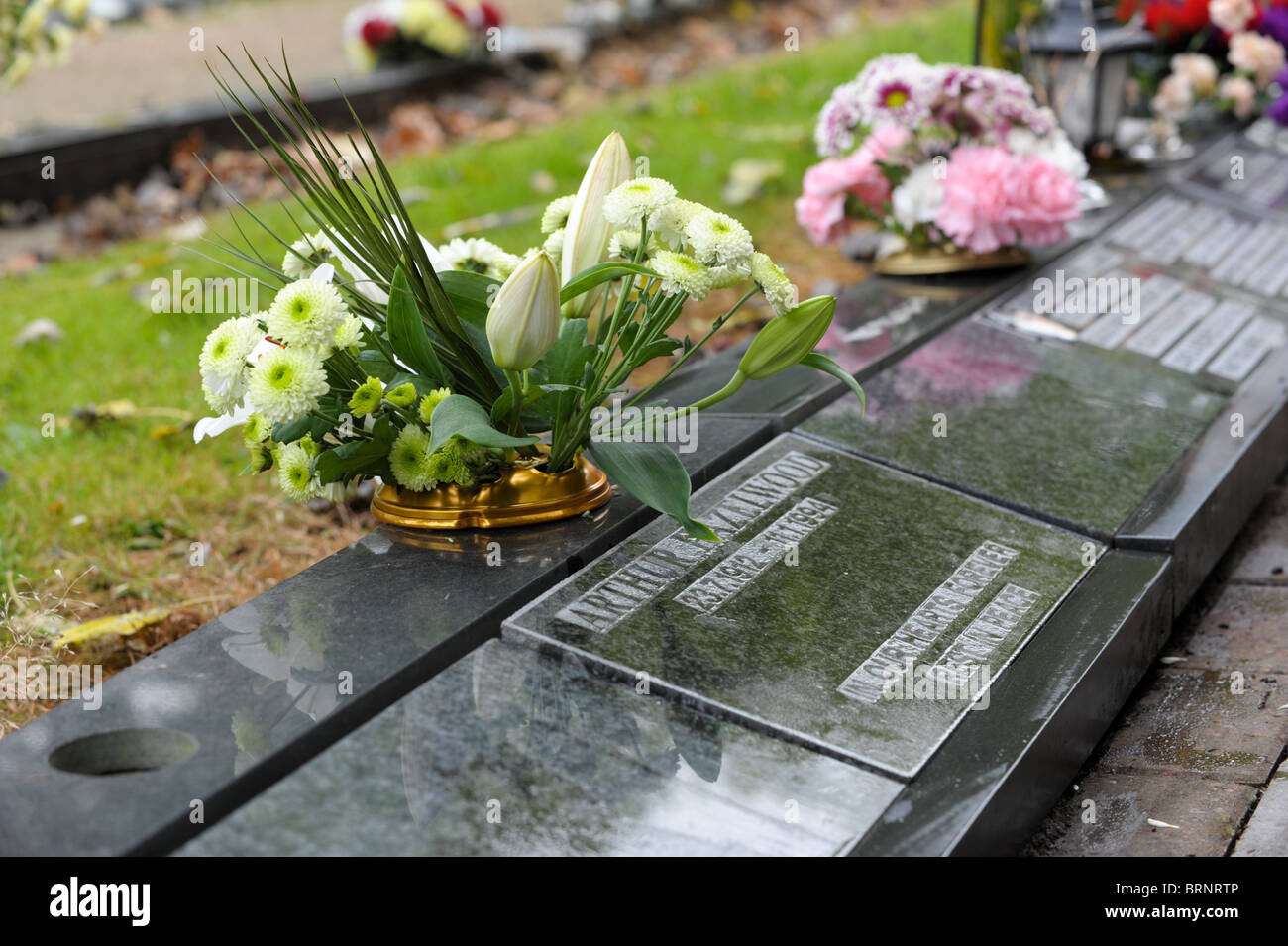 Lys Blanc et de fleurs dans un vase sur un trottoir en marbre noir dans un cimetière mémorial Banque D'Images