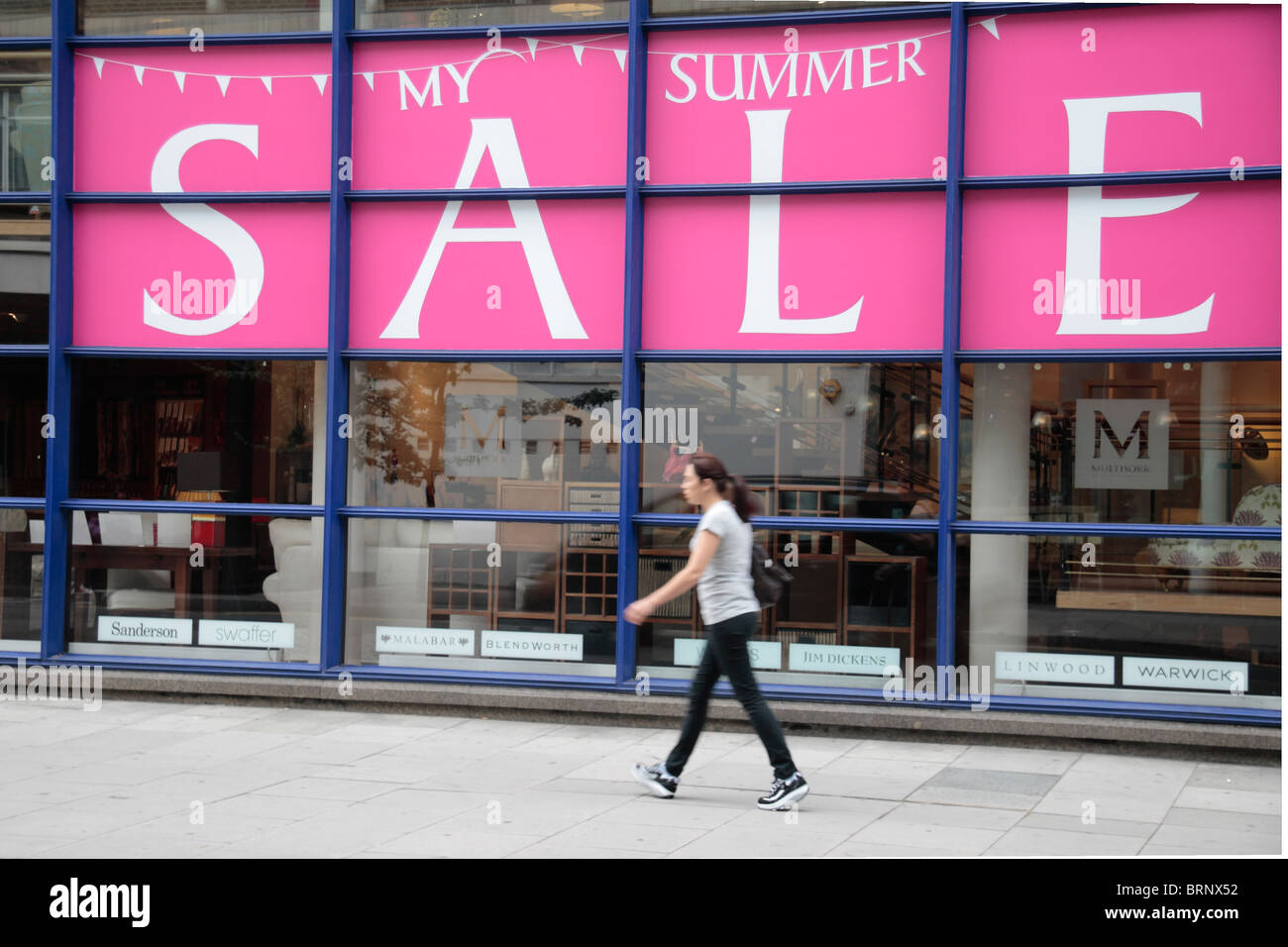 Femme marche passé un été massive signe à Maître Multiyork vente fabricants de meubles sur Tottenham Court Road, Londres, Royaume-Uni. Juillet 2010 Banque D'Images
