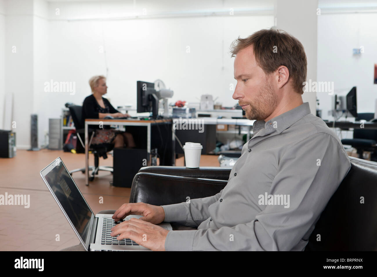 Man relaxing on sofa with laptop Banque D'Images