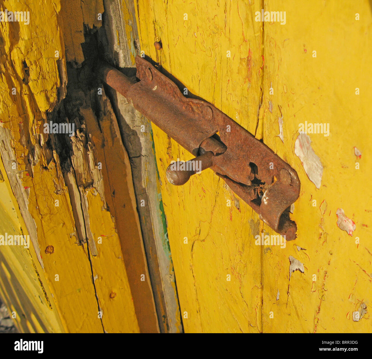 Boulon rouillé verrouillé dans une porte en bois jaune brisée Banque D'Images