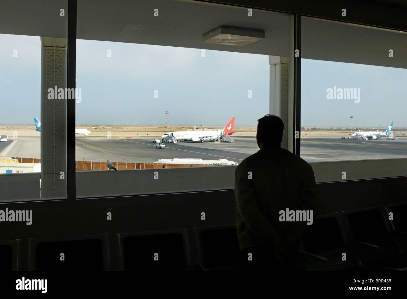Homme regardant à travers une fenêtre à l'aéroport. Banque D'Images