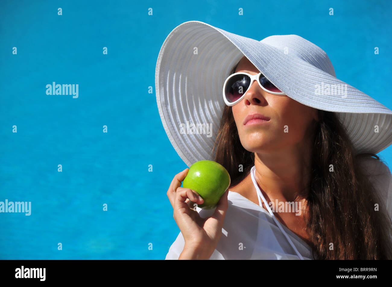 Belle sexy young woman eating apple près de la piscine Banque D'Images