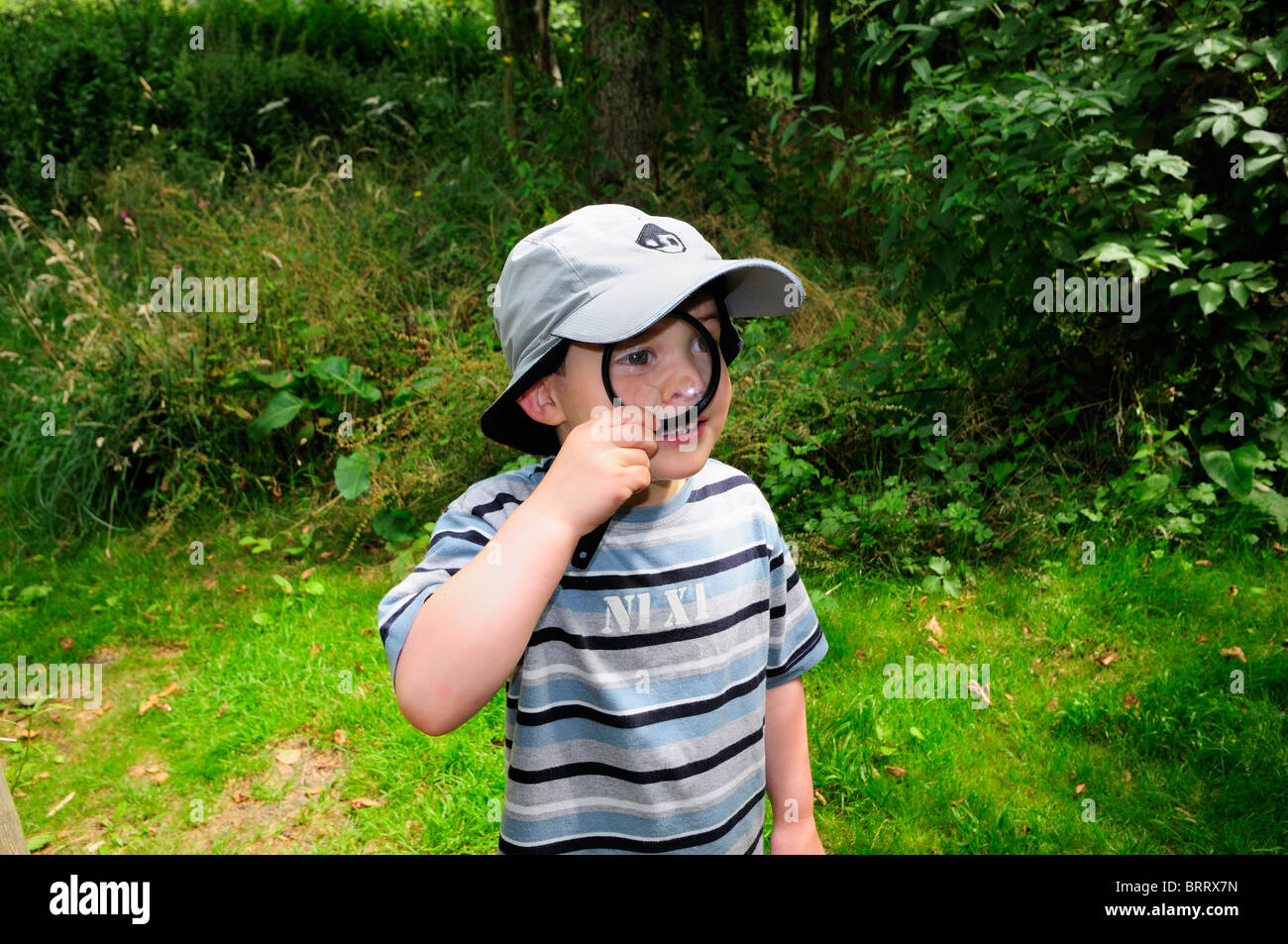 Jeune garçon bug hunt loupe mal à son oeil, hat, dépouillé haut Banque D'Images