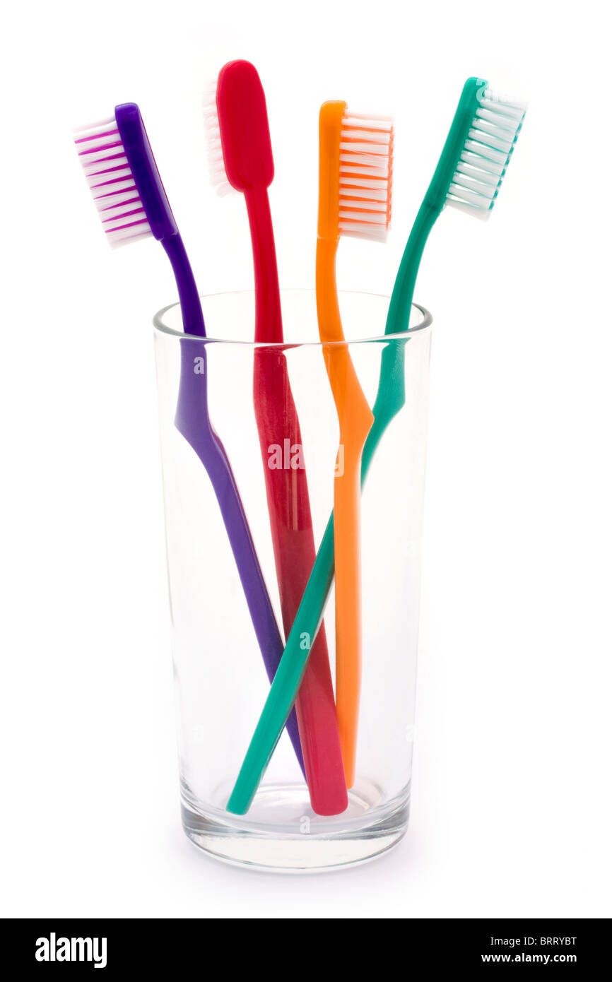 Brosses à dents de couleur dans un verre sur fond blanc Banque D'Images