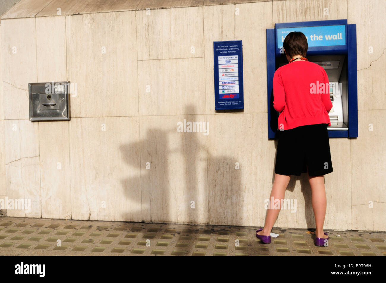 Une jeune femme retire de l'argent à partir d'un trou de la Barclays Bank dans le mur Cash Machine ATM, London, England, UK Banque D'Images