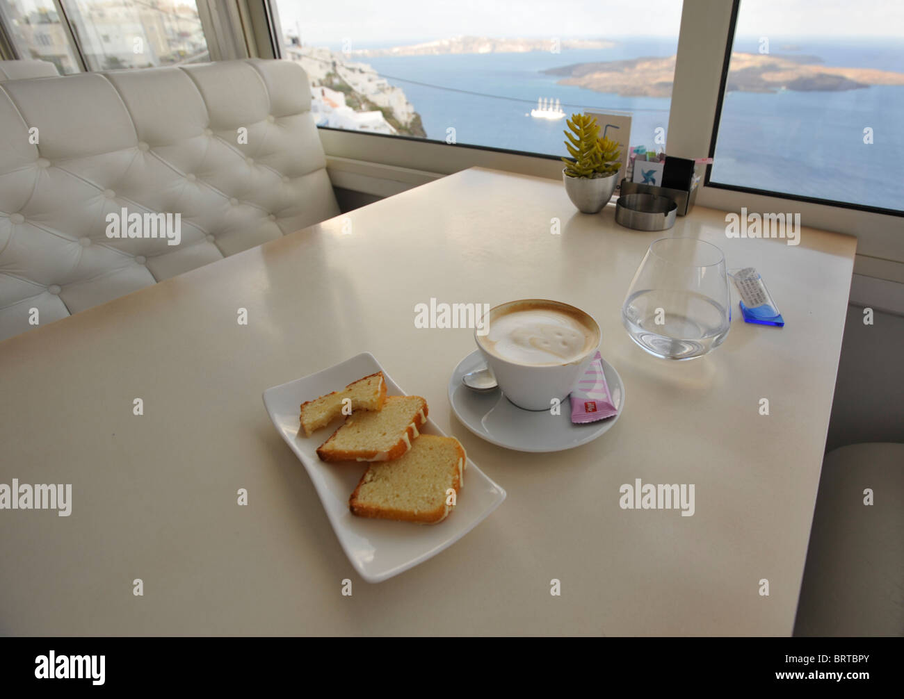 Cappuccino et pain à l'intérieur d'un café sur l'île grecque de Santorini avec vue sur la Caldeira Banque D'Images