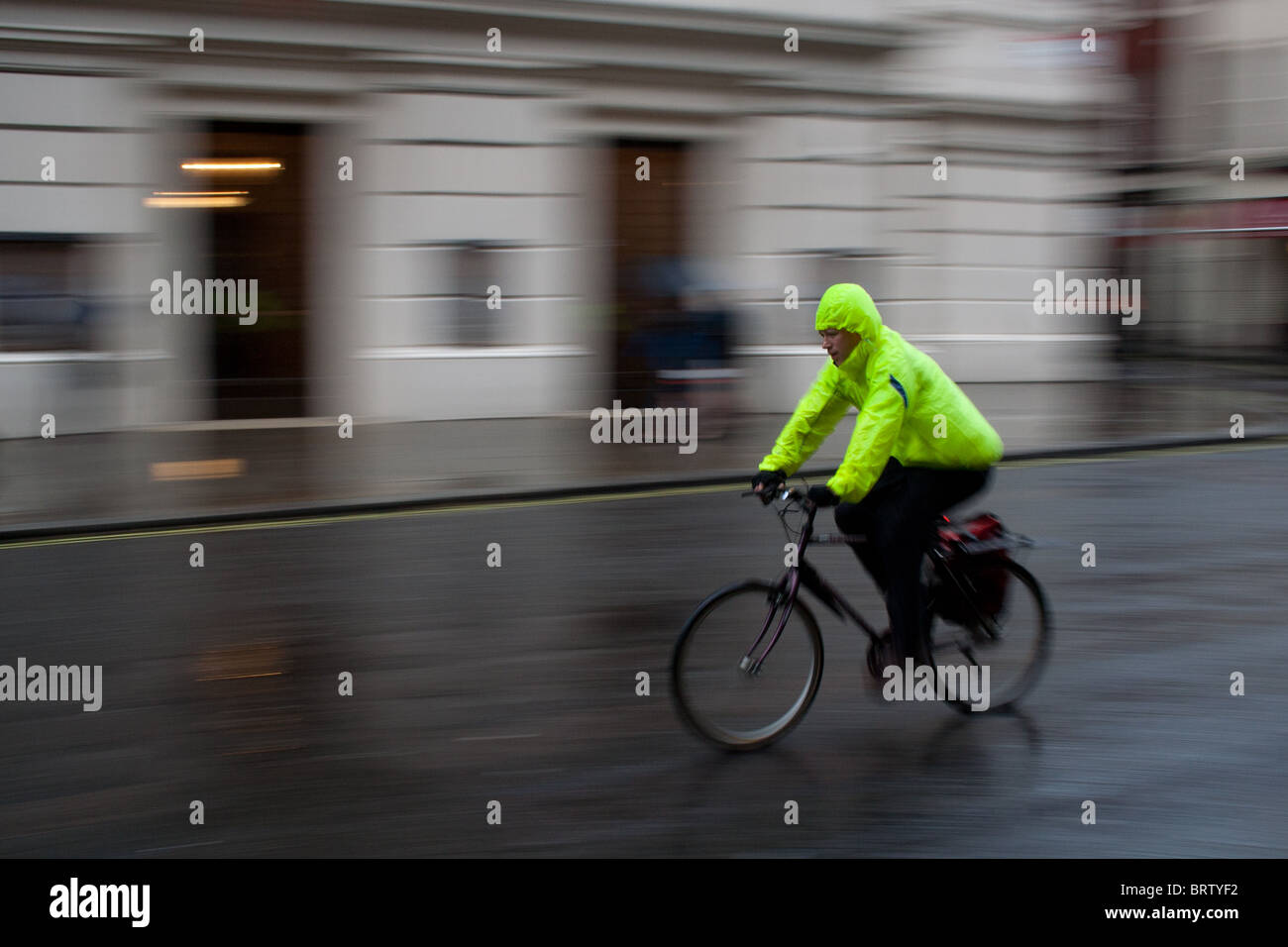 Un cycliste, équitation à travers les rues humides de Londres Banque D'Images