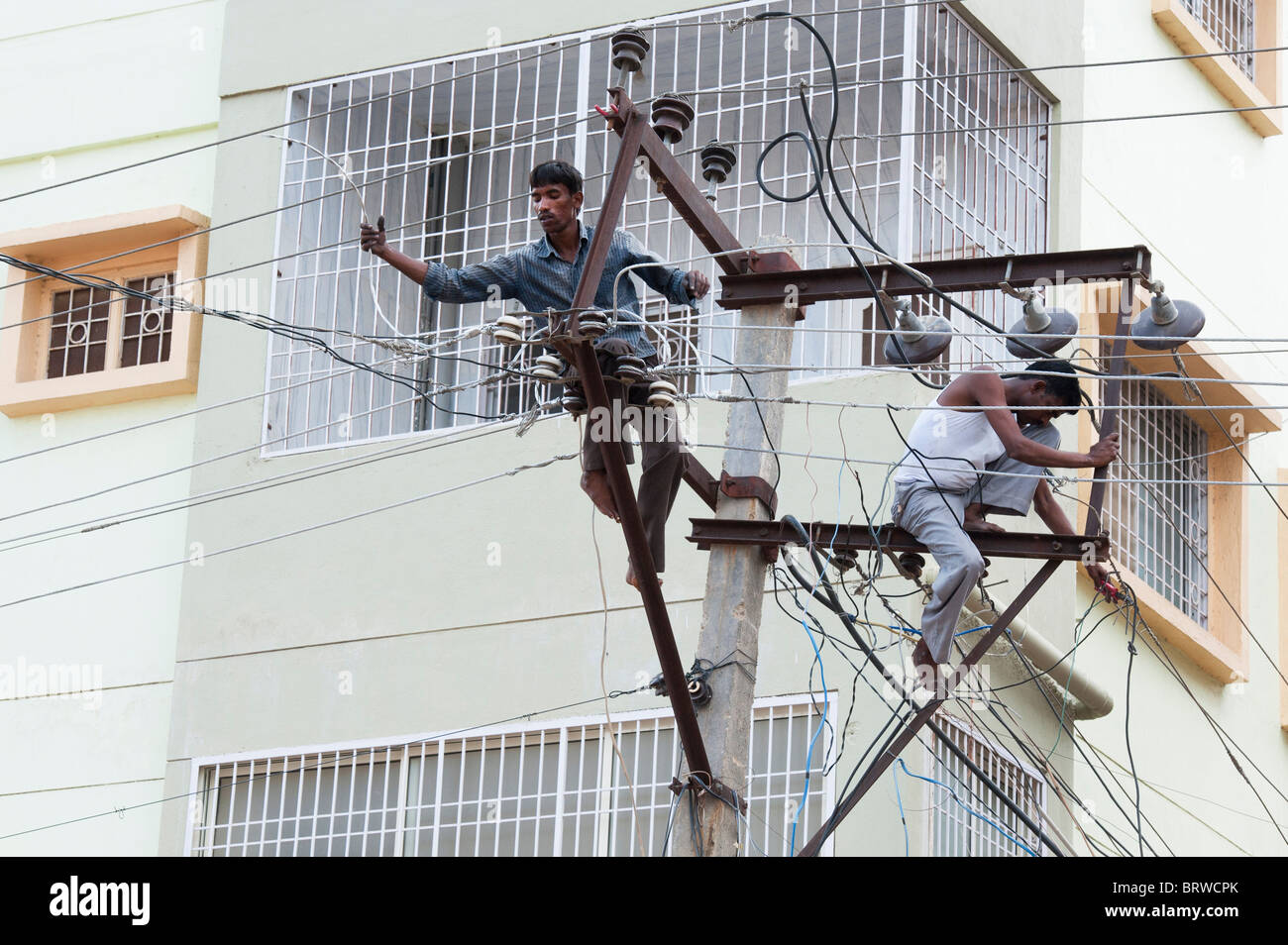 Electrician indiennes d'un pylône d'électricité dans les rues de Puttaparthi, Andhra Pradesh, Inde Banque D'Images