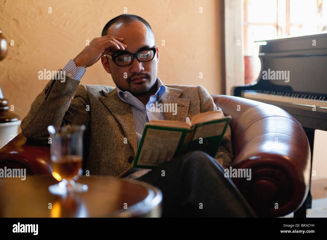 Man reading Book dans un fauteuil en cuir Banque D'Images