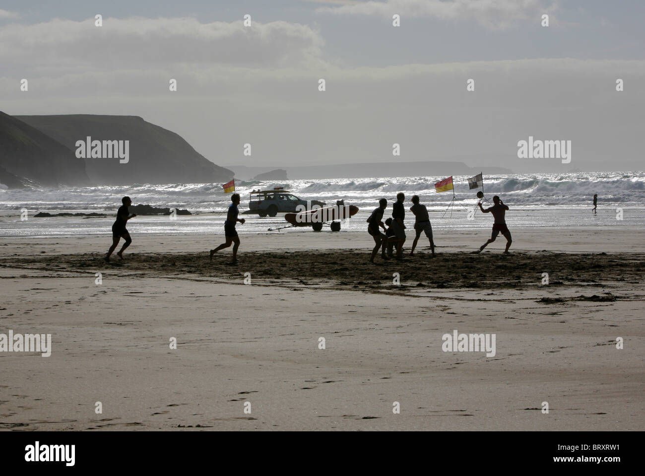 Les hommes à jouer au rugby sur la plage au crépuscule, Porthtowan, Cornwall, England, UK. Banque D'Images