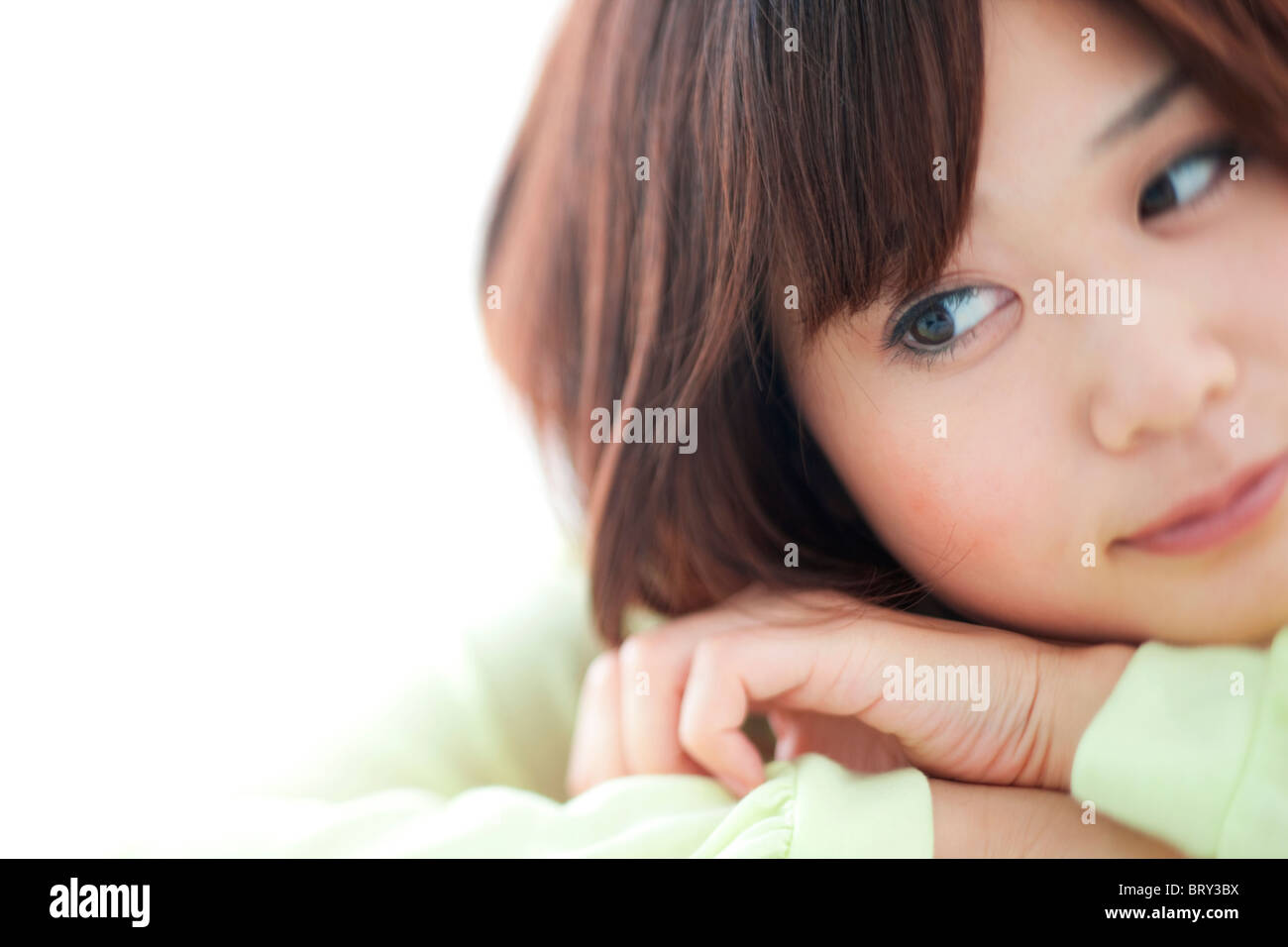 Young woman resting head on hands, Close up, fond blanc Banque D'Images
