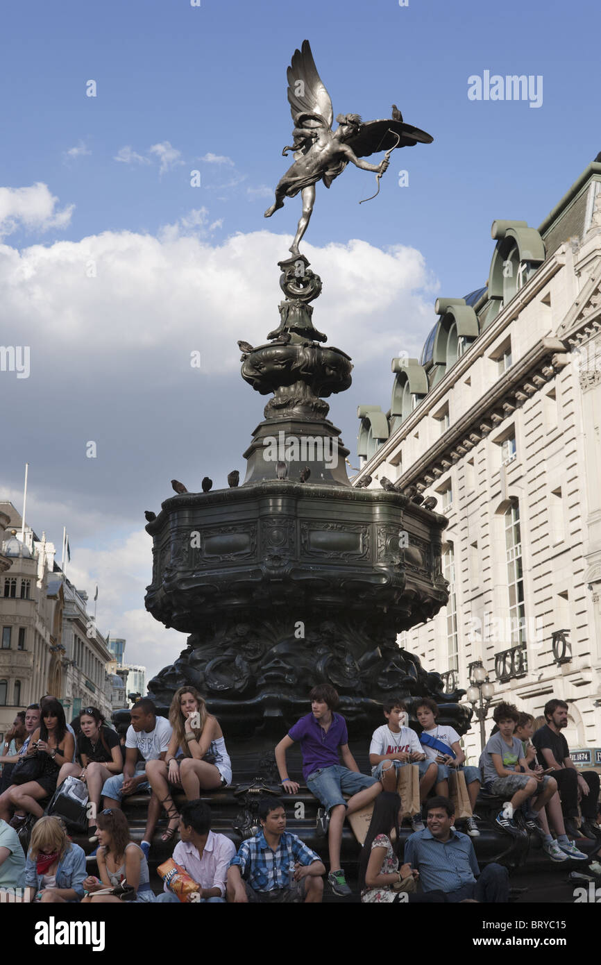 Les jeunes gens assis sous la statue d'Eros à Piccadilly Circus, l'été, Londres, UK Banque D'Images