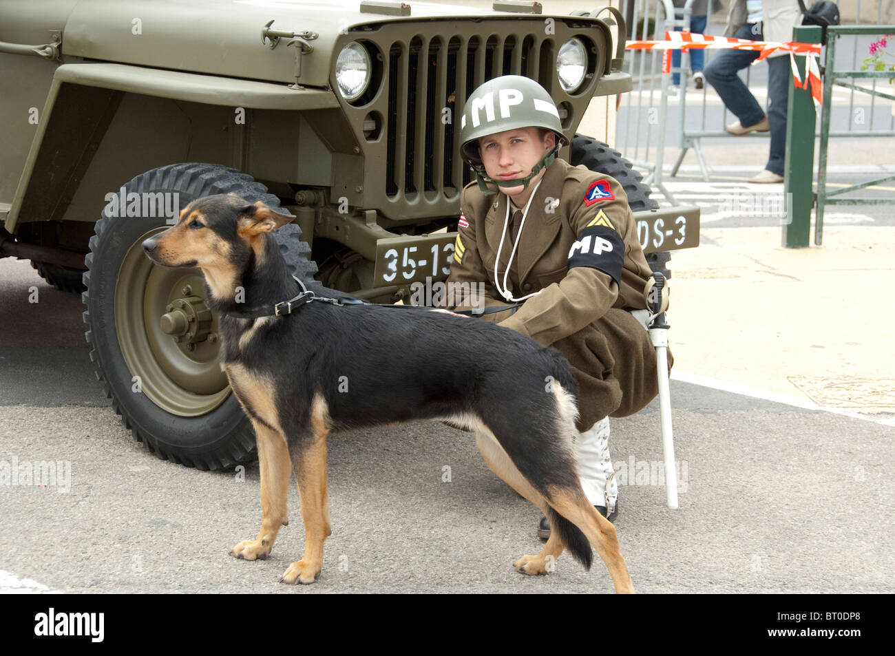 France, Normandie, Arromanches. Jeune homme en uniforme militaire US VINTAGE MP avec chien de garde. 66e anniversaire de D-Day. Banque D'Images