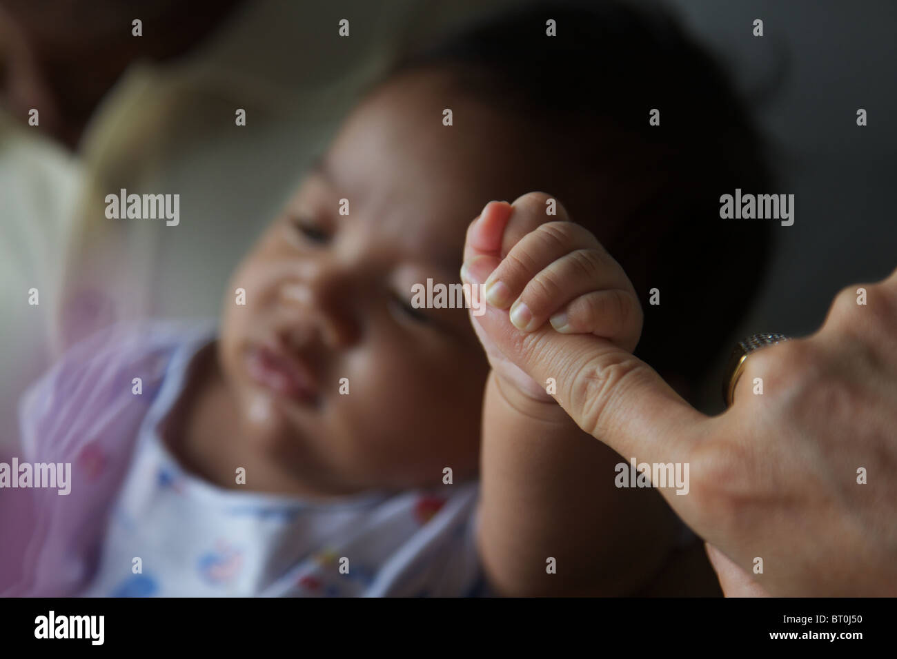 Un gros plan d'une 2 mois musulmans thaïlandais baby boy holding à un doigt, adultes Banque D'Images