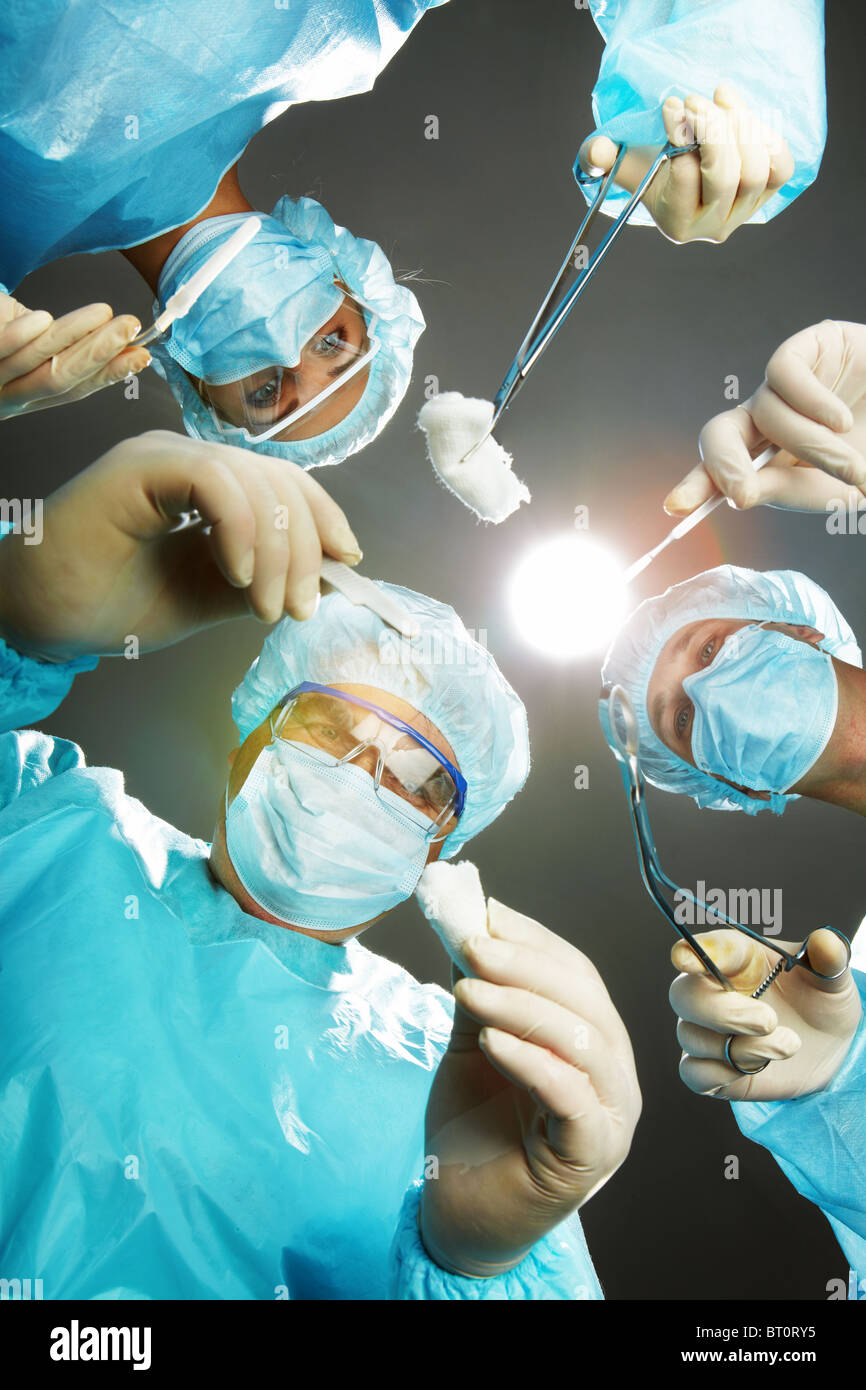 Trois chirurgiens se plier plus d'un patient avec des forceps Banque D'Images