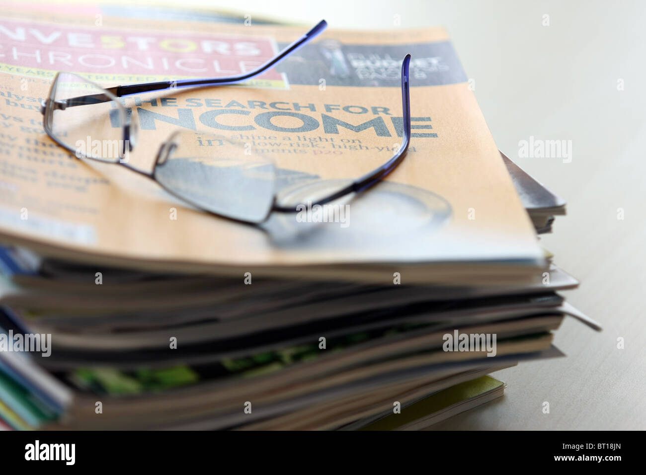 Spectacles sur une pile de magazines financiers Banque D'Images